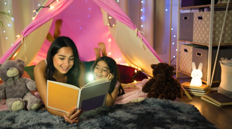 Two sisters read inside their bedroom fort
