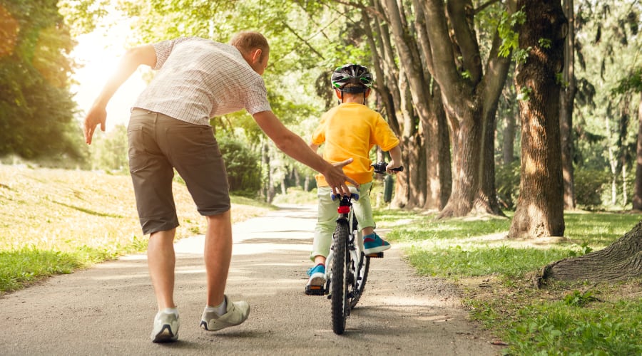 A father teaches his son how to ride a bike
