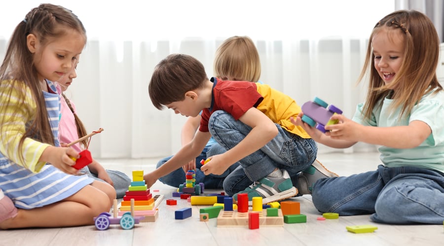 A group of children plays with wooden blocks