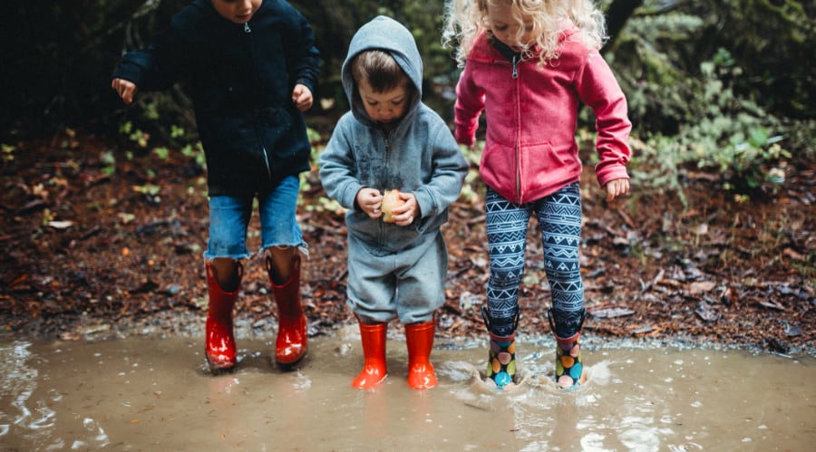 Adventure Pediatrics Three small kids jumping in a mud puddle